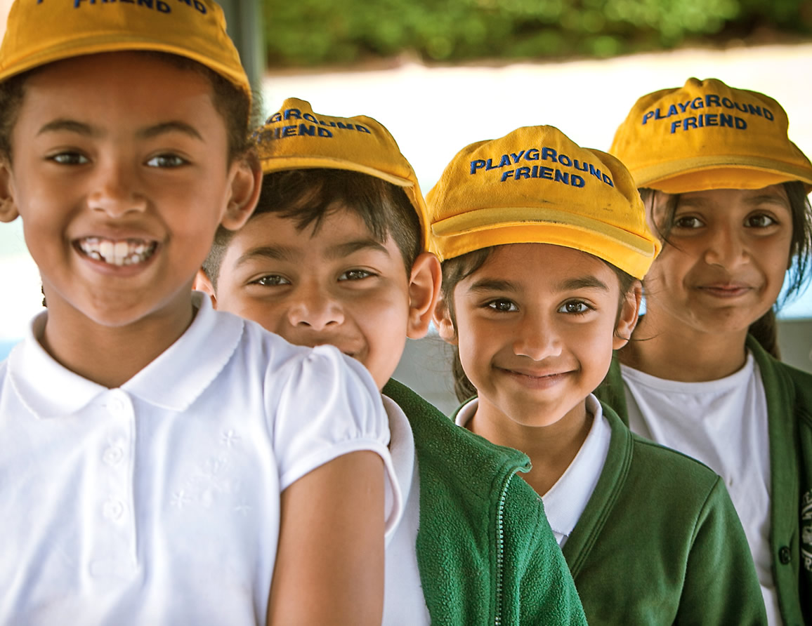 Children wearing Playground Friend hats smiling